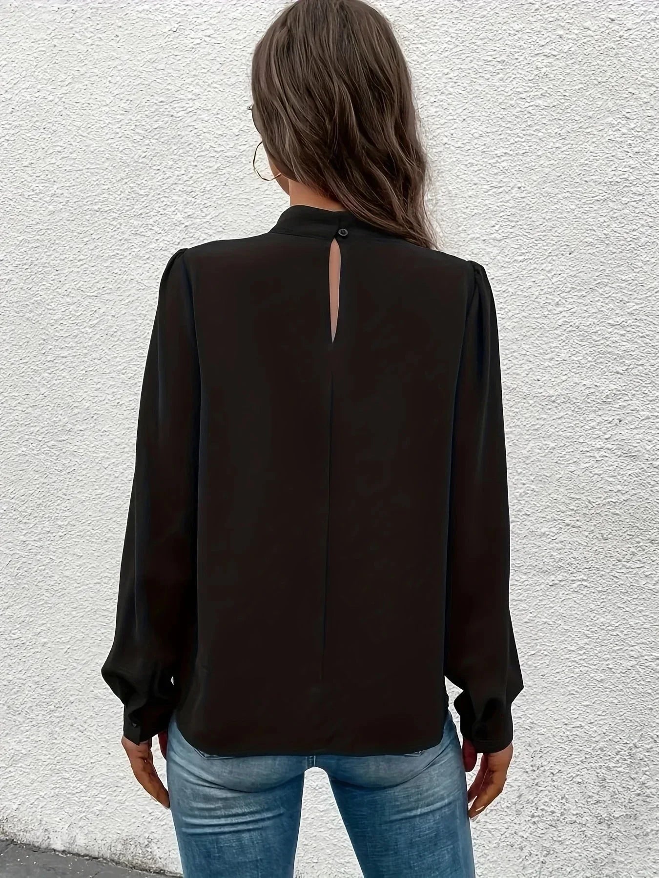 Haut noir à manches longues pour femme, coupe élégante, en tissu léger avec des détails raffinés.