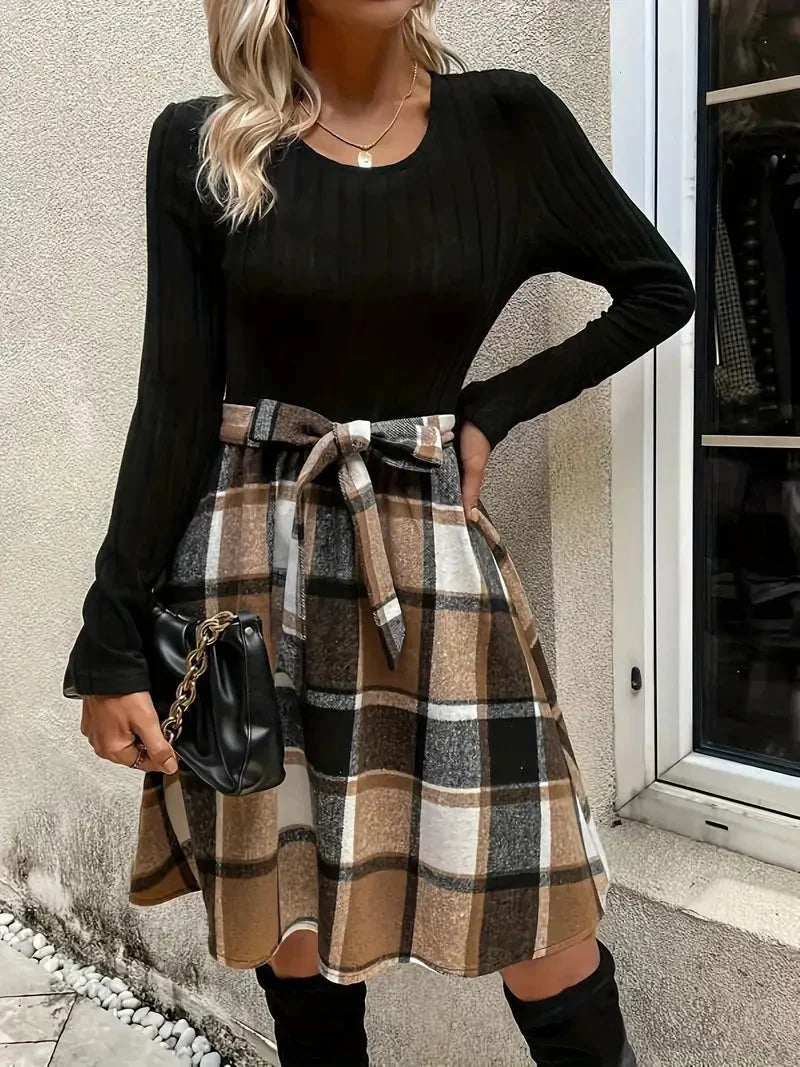Haut ajusté noir en coton avec manches longues, associé à une jupe évasée à carreaux en tissu léger.