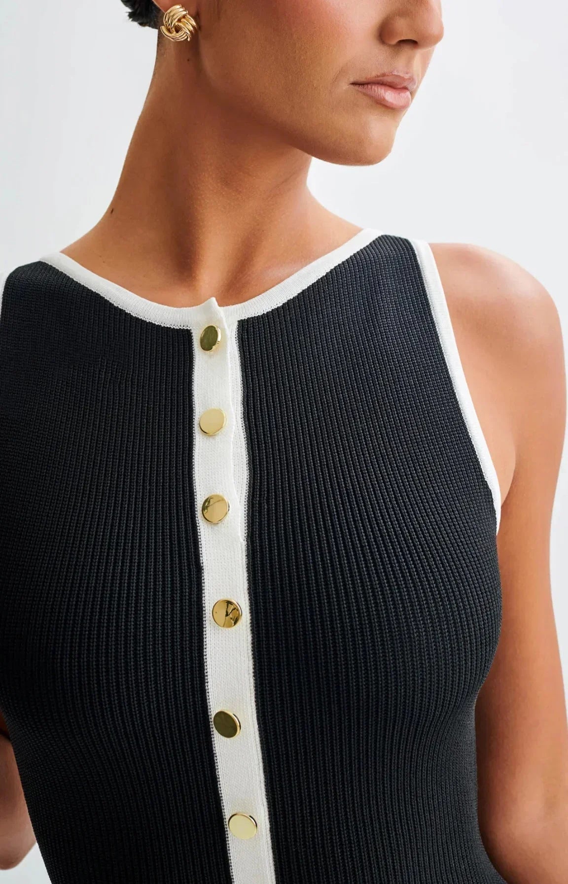 Robe midi noire en coton avec boutons contrastés sur le devant, manches courtes et taille cintrée pour un look élégant.
