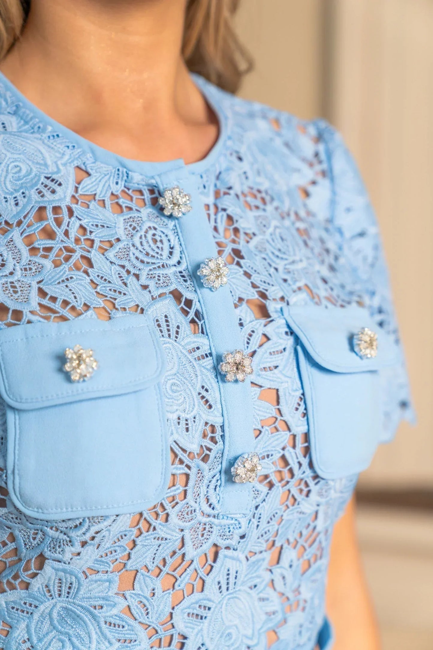 Robe mini femme bleue en dentelle avec manches courtes et détail floral sur le tissu, idéale pour les sorties estivales.