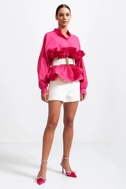 Blouse rose pour femme avec volants et manches volumineuses, en tissu léger et respirant.