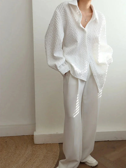 Blouse blanche en tissu texturé, manches sculptées, au design élégant et moderne pour un look raffiné.