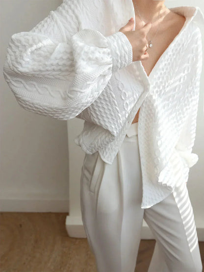 Blouse femme blanche en tissu texturé, avec manches sculptées, offrant un style unique et une coupe confortable.