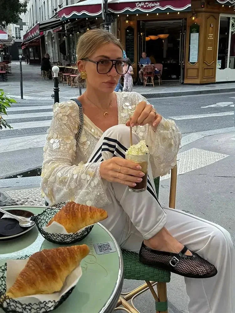 Blouse ivoire en polyester avec paillettes scintillantes et col en V, parfaite pour une tenue élégante.