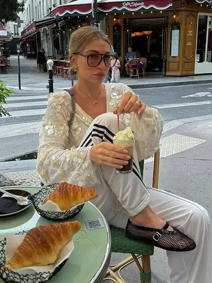 Blouse ivoire en polyester avec paillettes scintillantes et col en V, parfaite pour une tenue élégante.