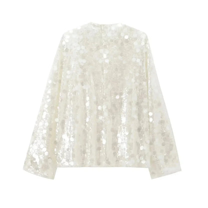 Blouse ivoire à paillettes avec col en V, en tissu léger, parfaite pour une tenue élégante et festive.