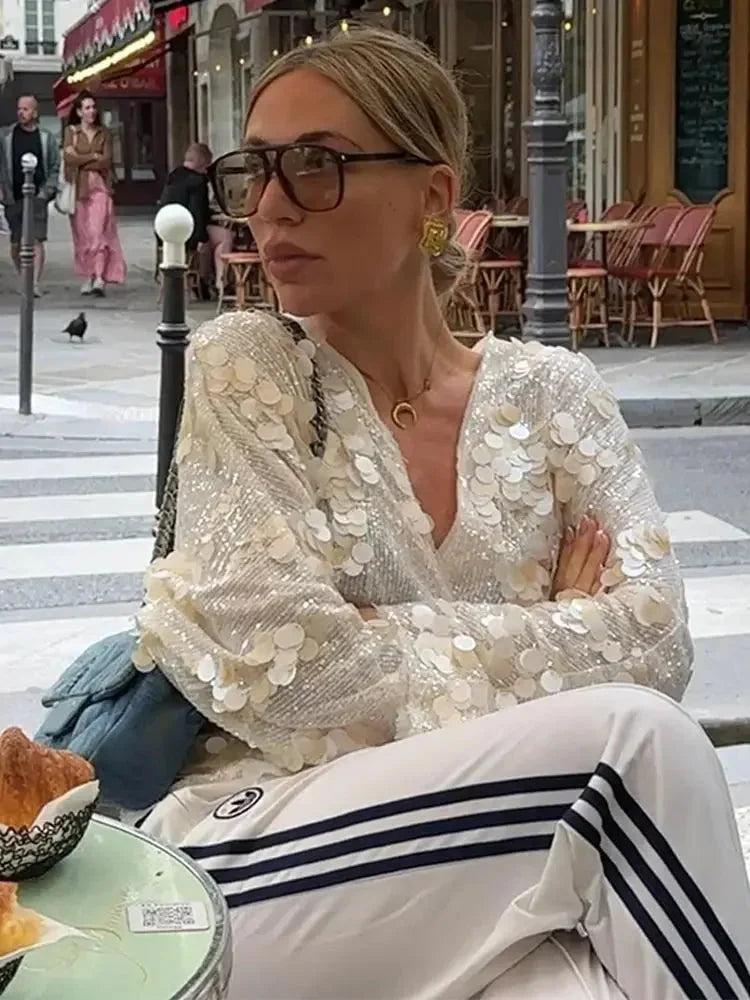 Blouse femme ivoire en tissu léger, ornée de paillettes et dotée d'un col en V élégant pour un style féminin.