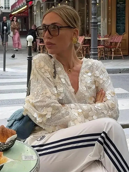 Blouse femme ivoire en tissu léger, ornée de paillettes et dotée d'un col en V élégant pour un style féminin.