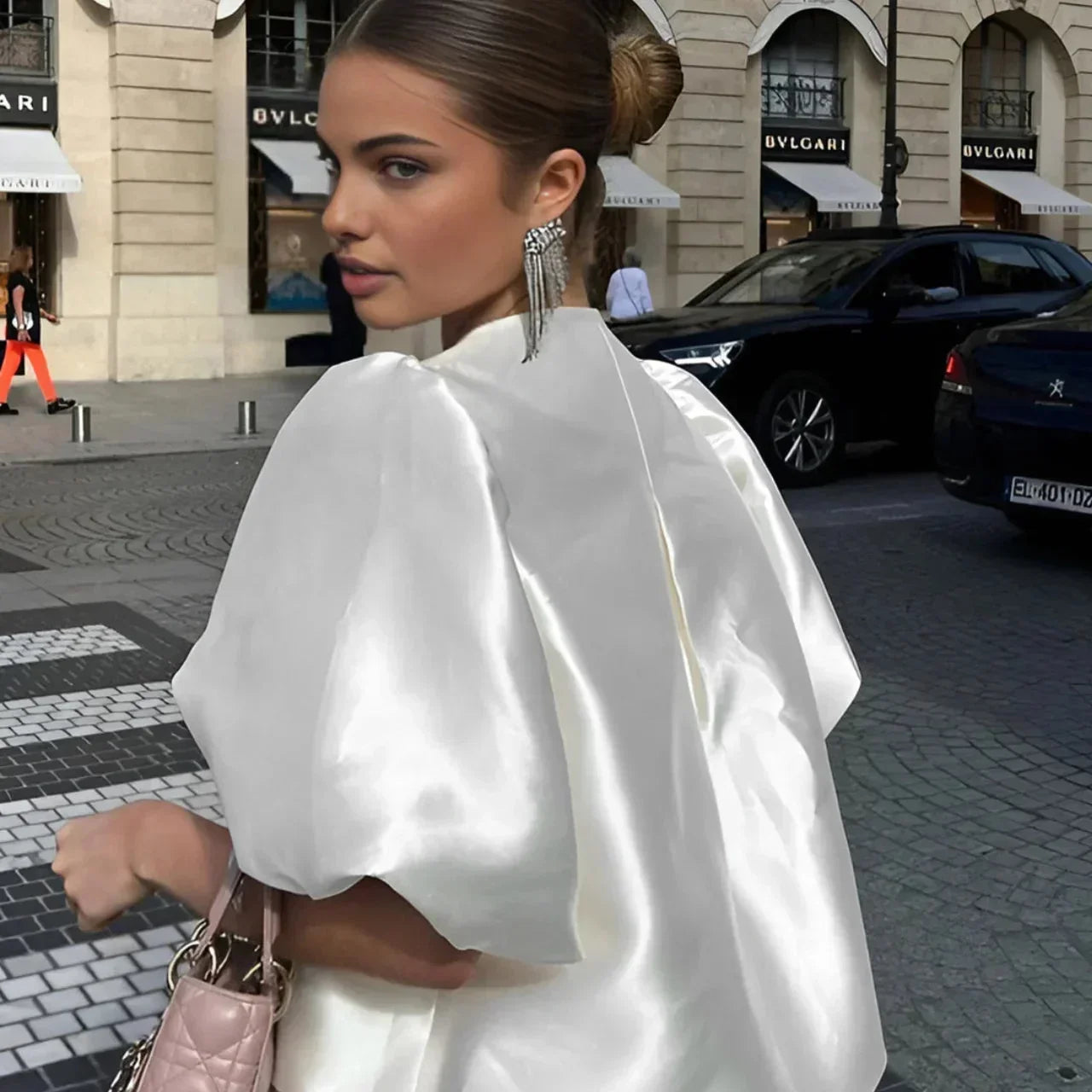Blouse en satin blanc avec manches bouffantes, offrant une silhouette élégante et un tissu doux au toucher.