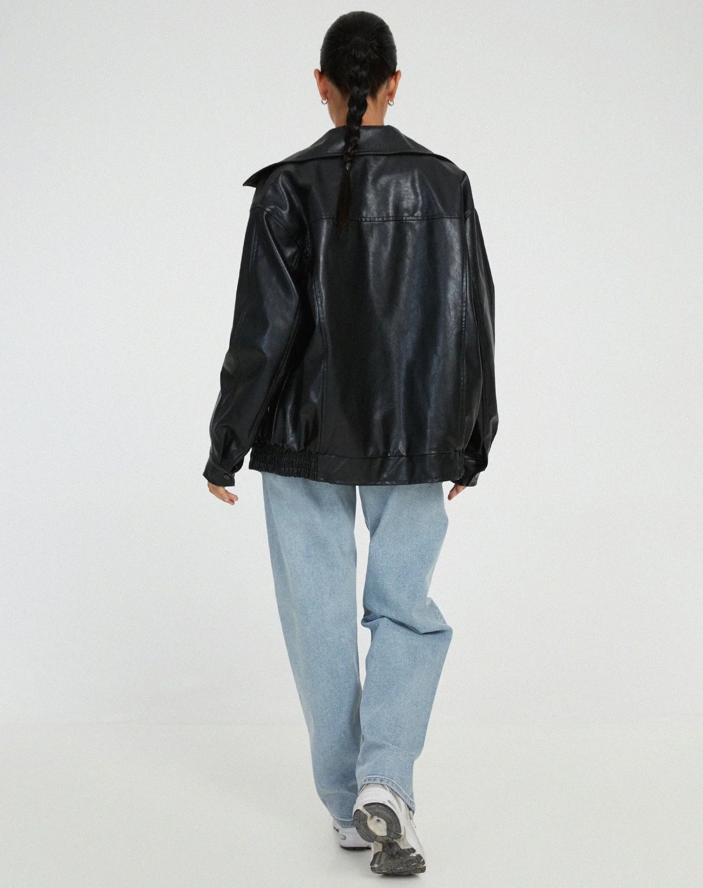 Blouson femme noir en similicuir, style motard, avec fermeture éclair et deux poches latérales.