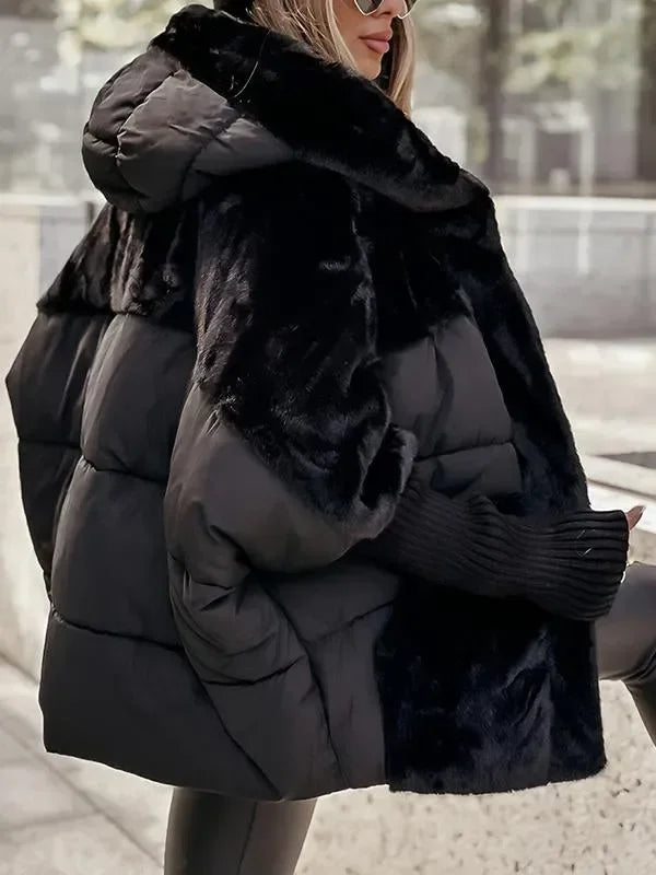 Cape d'hiver matelassée noire avec capuche et col en fausse fourrure, conçue pour les journées froides.