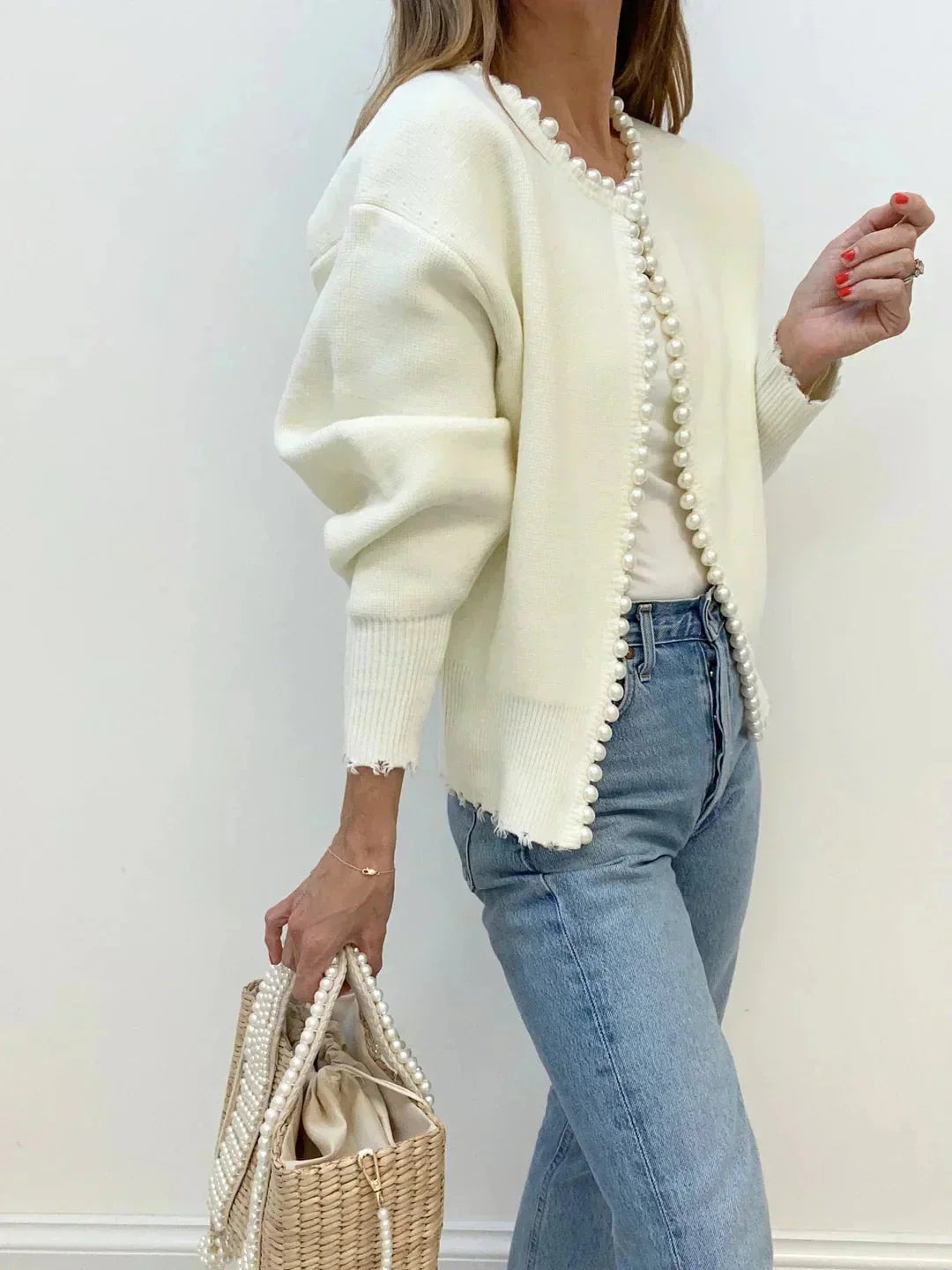 Cardigan femme ouvert en blanc, avec bordures en perles et design en tricot fin.