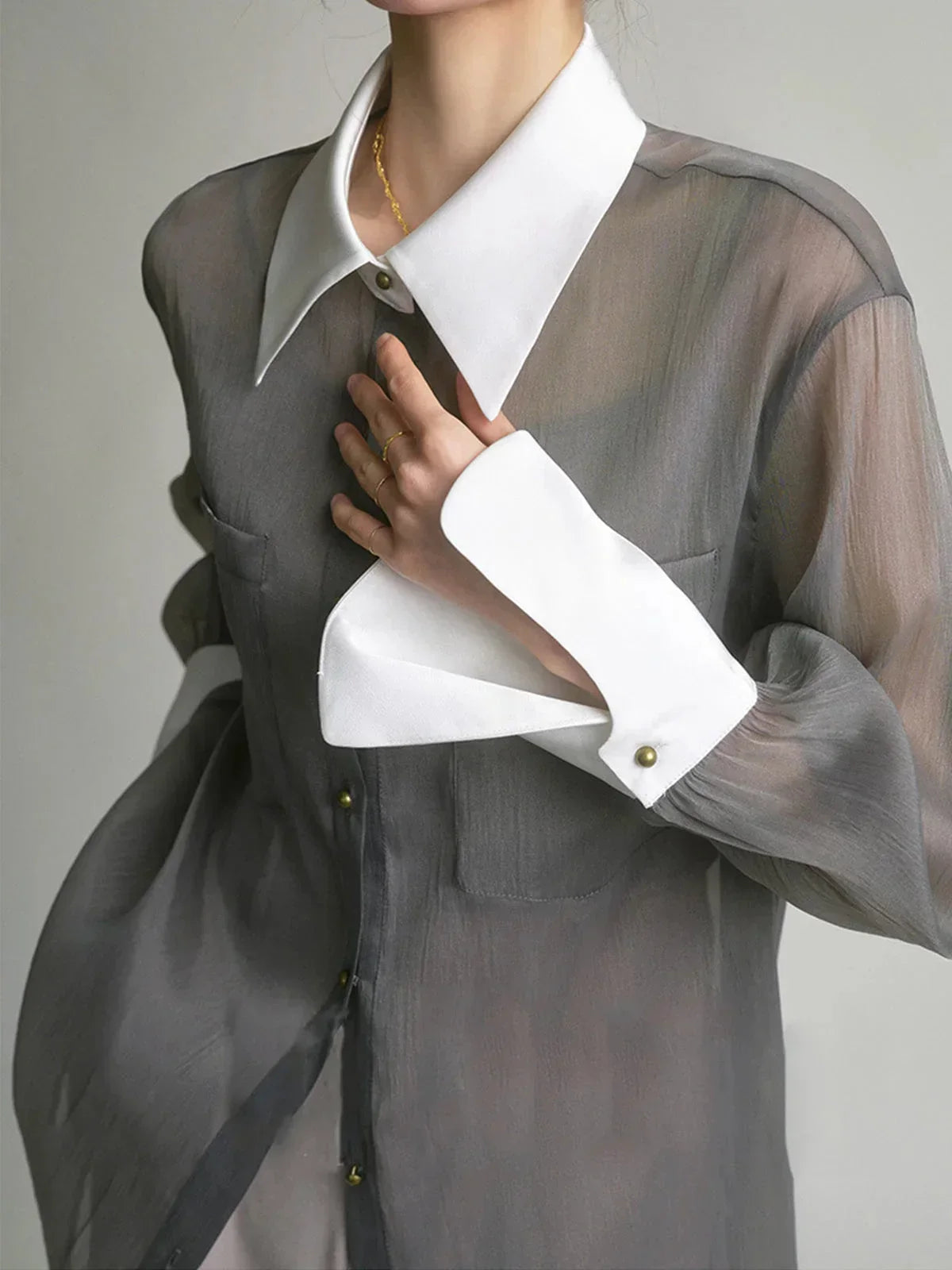 Chemisier femme transparent en tissu léger, avec boutons et col élégant, idéal pour une tenue décontractée ou habillée.