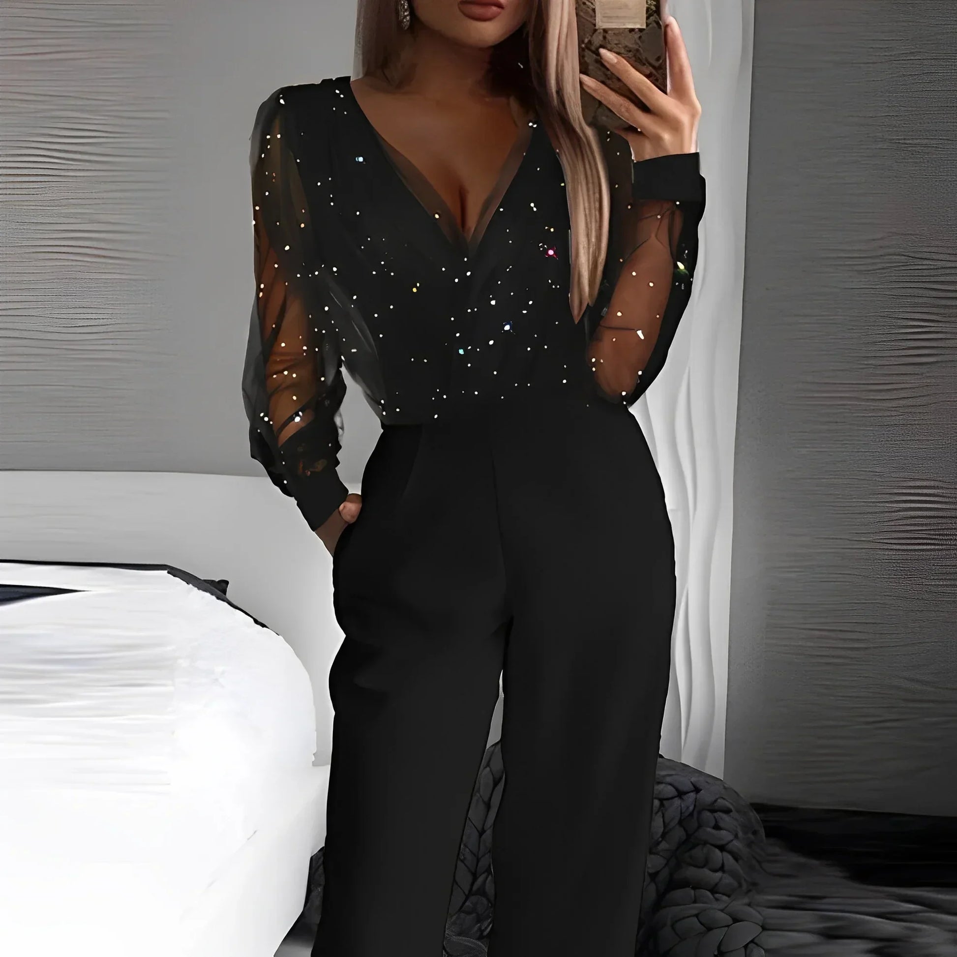 Combinaison femme noire à col V, détails transparents et jambes évasées en tissu léger.