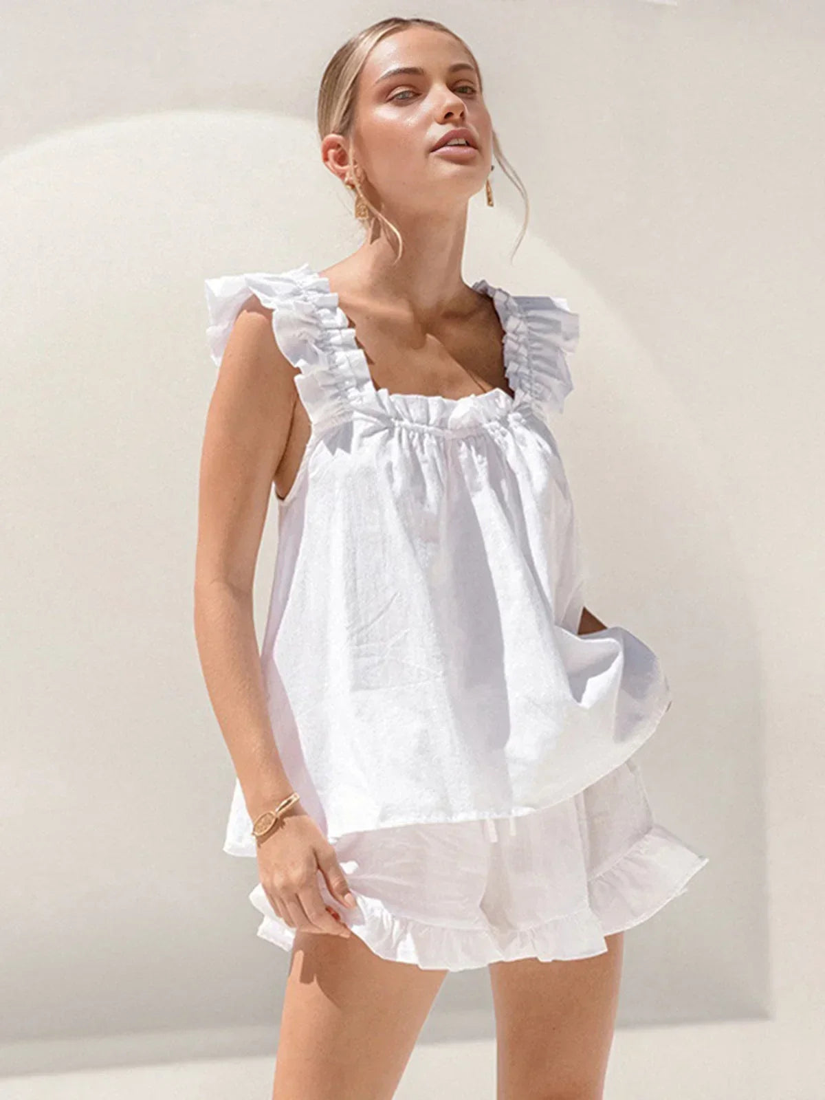 Ensemble femme en blanc, haut sans manches à volants avec short assorti, en tissu léger et respirant pour un confort estival.