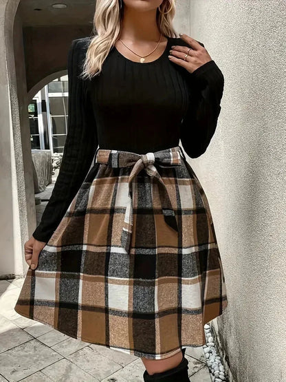 Haut ajusté noir en tissu doux, manches longues, associé à une jupe évasée à carreaux pour un style chic et intemporel.