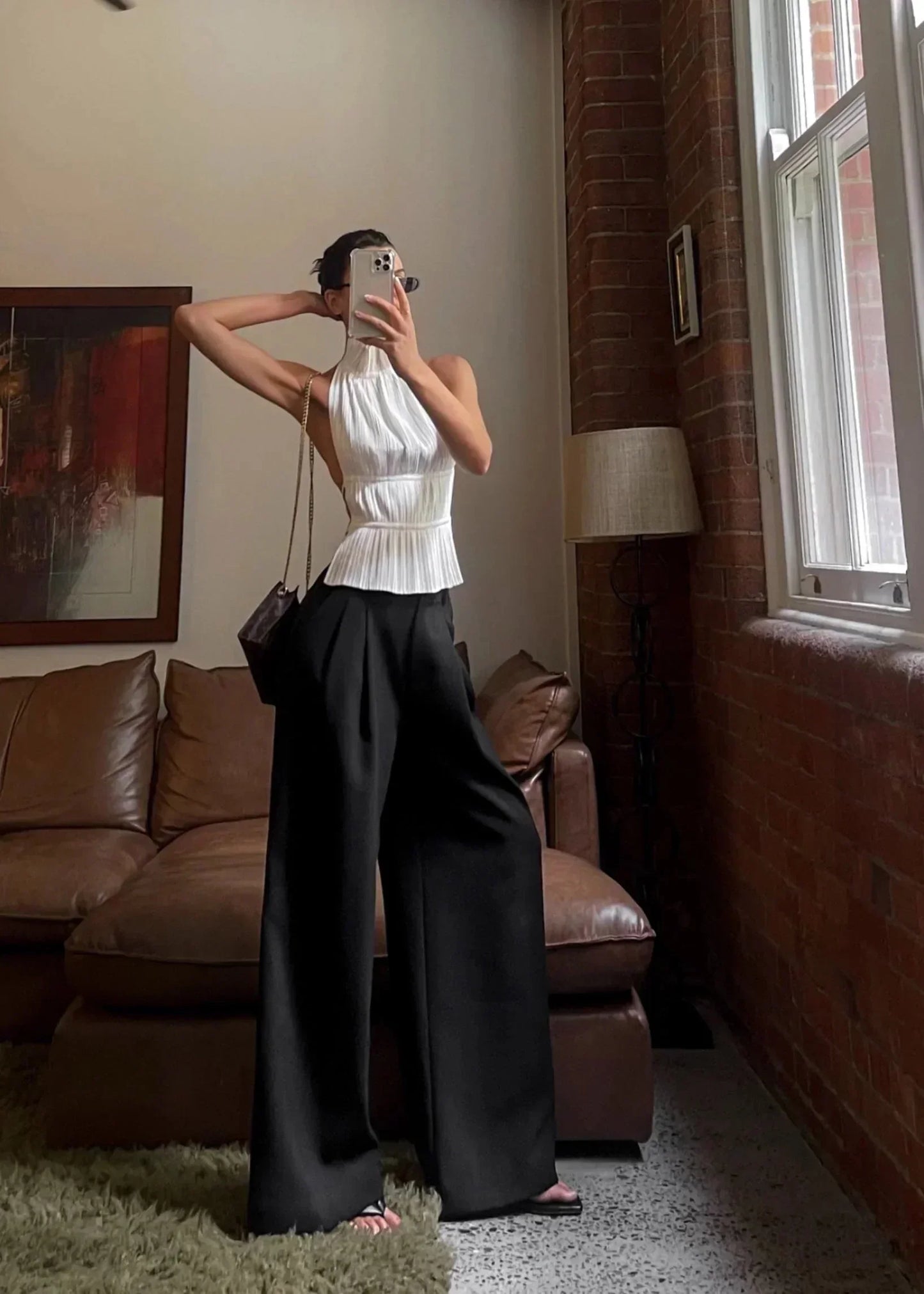 Haut femme dos-nu en tissu léger avec des détails en chaîne métallique sur les bretelles pour un look élégant.