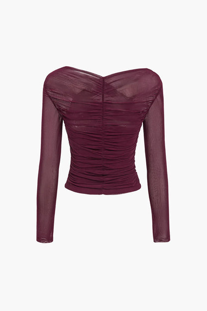 Haut femme noir à manches longues, transparentes et plissées, en tissu léger.