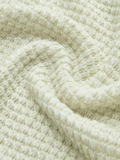 Haut noir à manches longues en maille texturée, adapté pour des tenues d'automne.