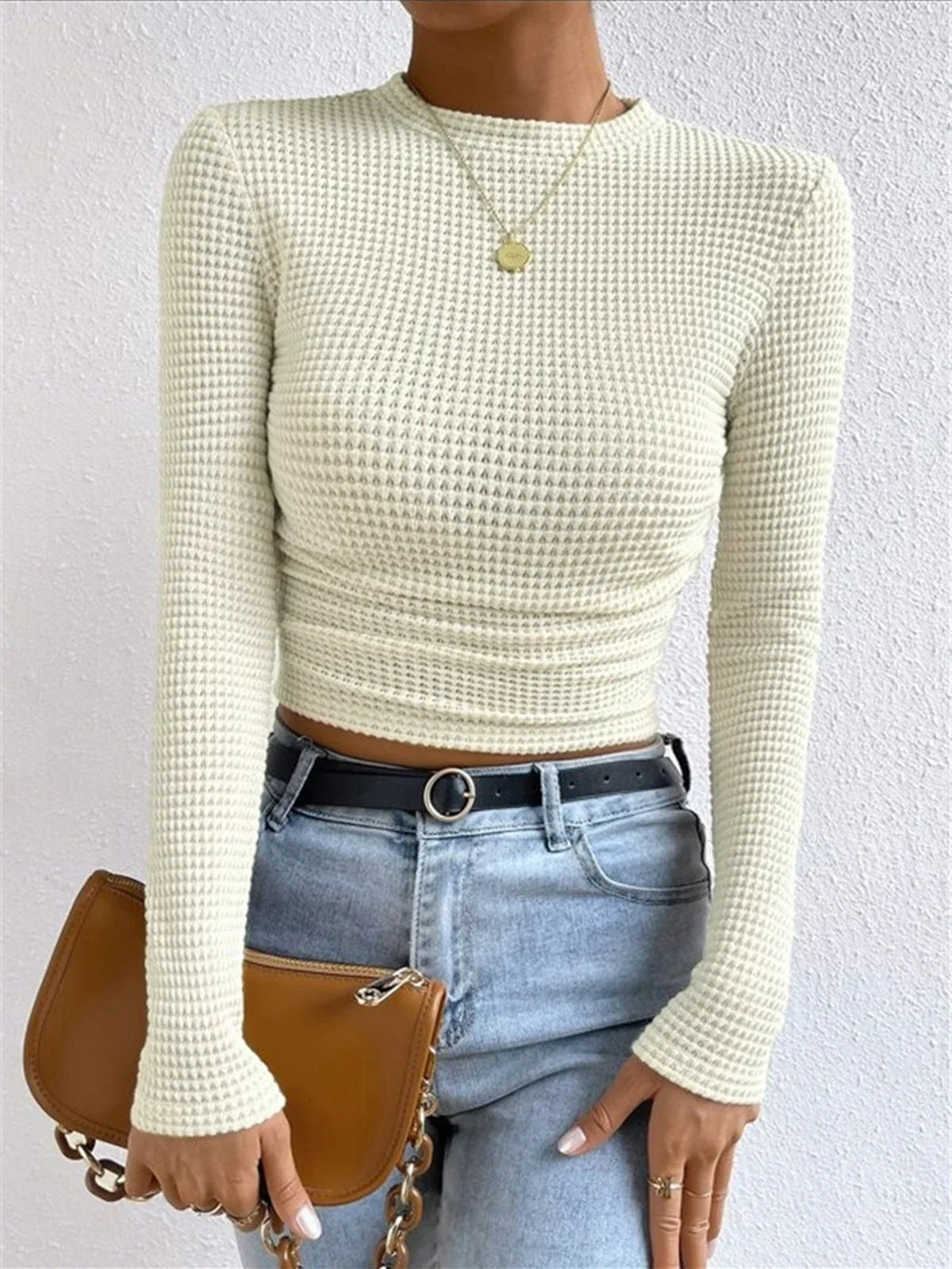 Haut beige à manches longues en maille texturée, coupe confortable et polyvalente pour diverses occasions.