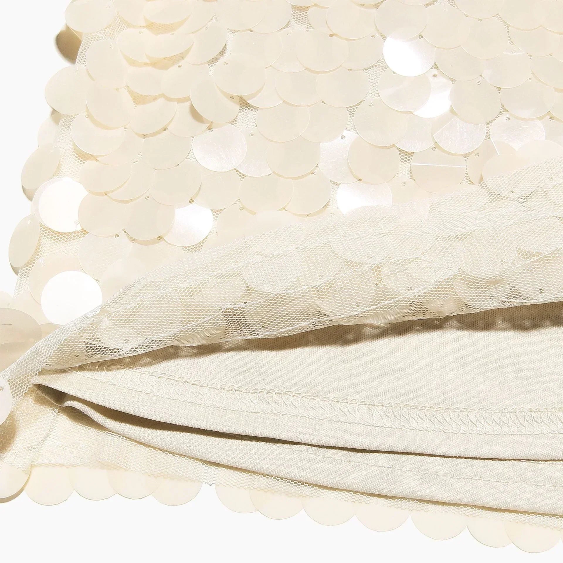 Jupe courte ivoire à sequins, conçue en tissu léger, avec un design scintillant et une coupe flatteuse pour toutes occasions.