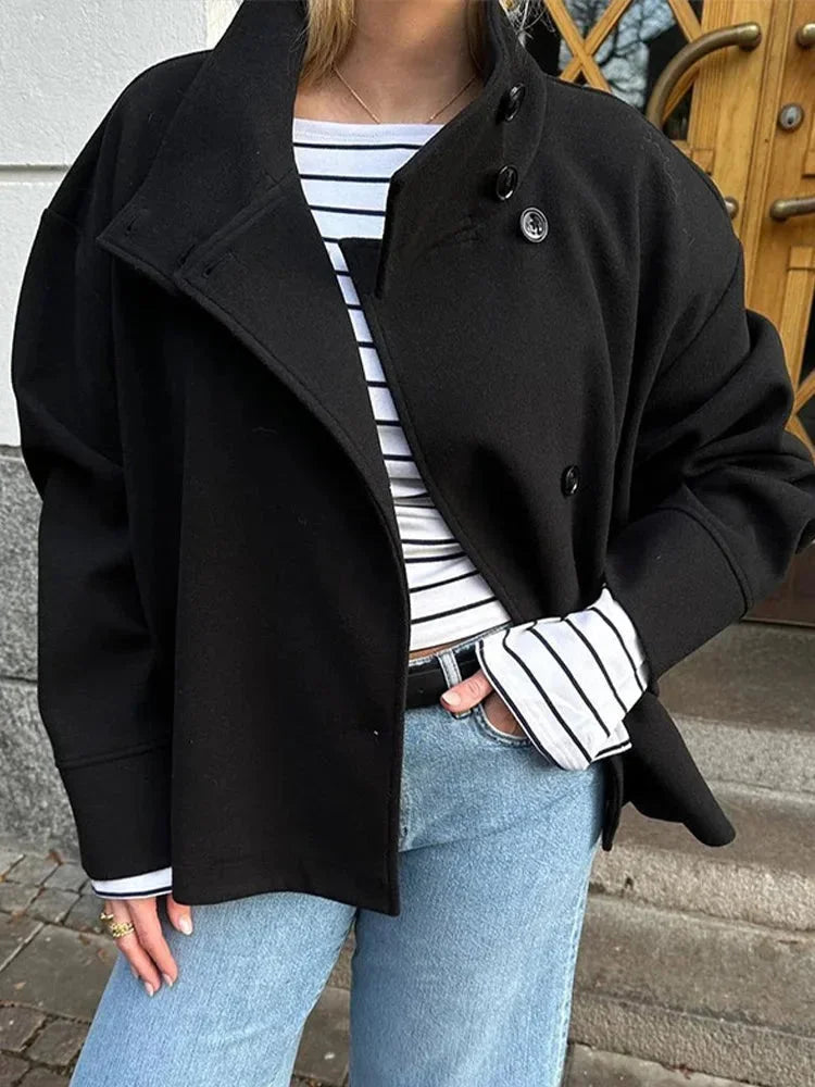 Manteau court femme bleu foncé avec boutons et col montant, conçu pour les saisons de transition.