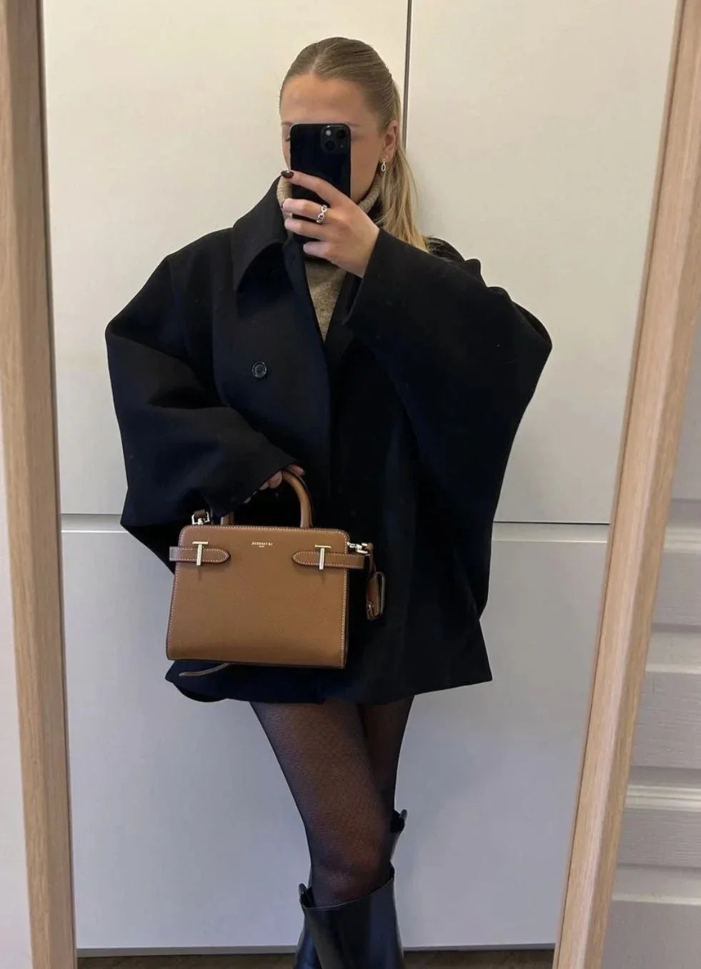 Manteau ample noir pour femme avec grands revers et boutons, adapté pour les journées fraîches et les tenues décontractées.