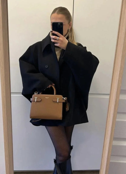 Manteau ample noir pour femme avec grands revers et boutons, adapté pour les journées fraîches et les tenues décontractées.
