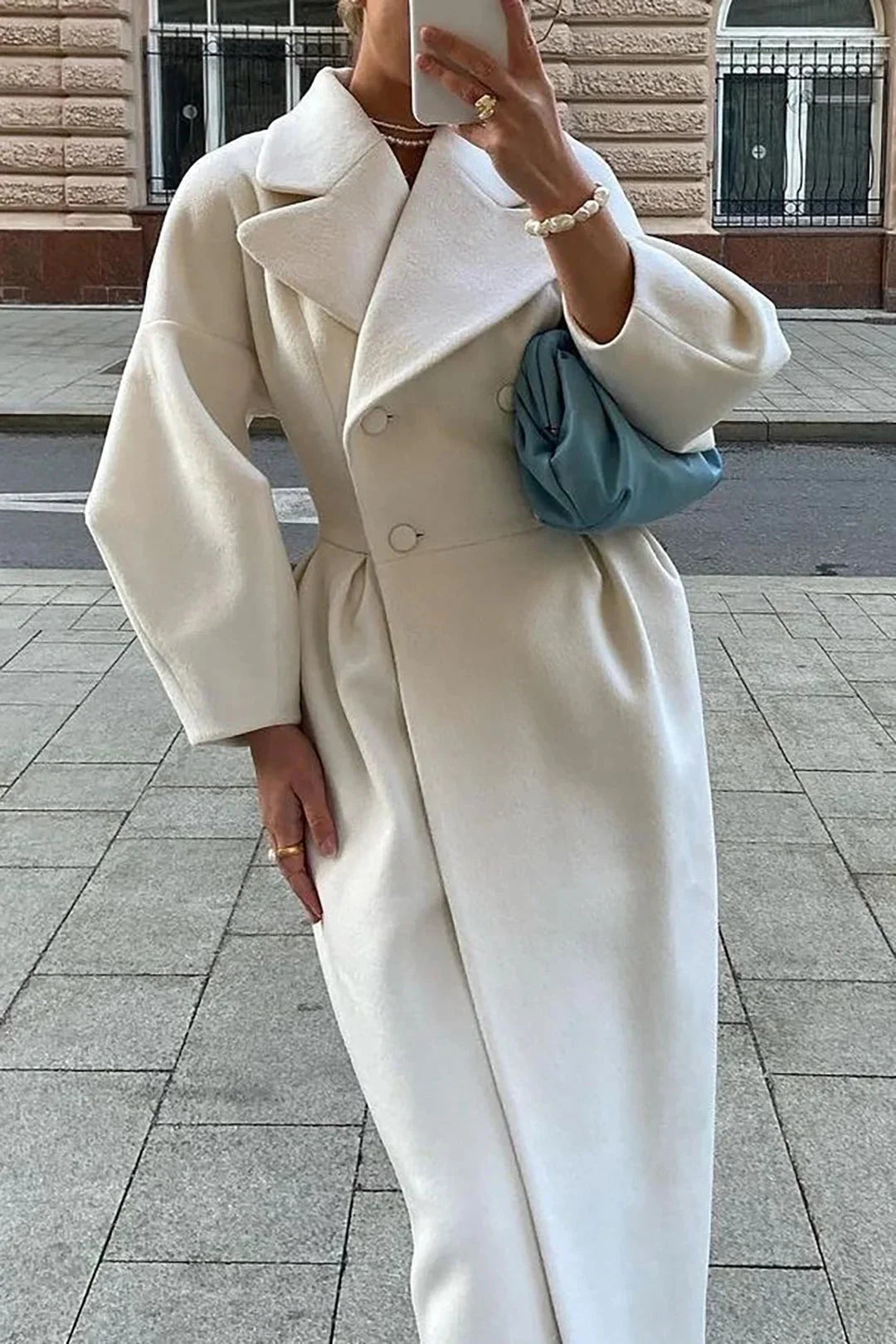 Manteau long blanc pour femme, col large, silhouette minimaliste, en tissu doux.