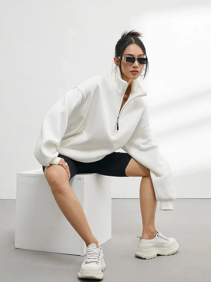 Pull à capuche femme oversize blanc en coton, avec demi-zip et coupe décontractée.