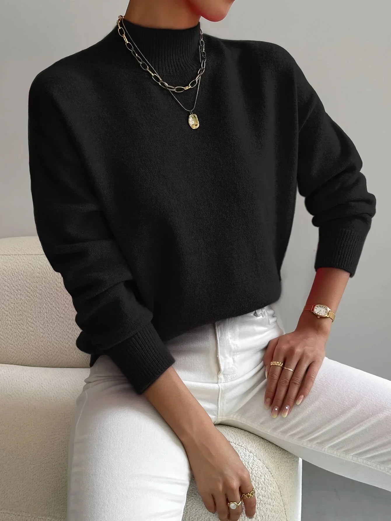 Pull féminin blanc à col montant, en tissu extensible, à manches longues, adapté pour les journées fraîches.