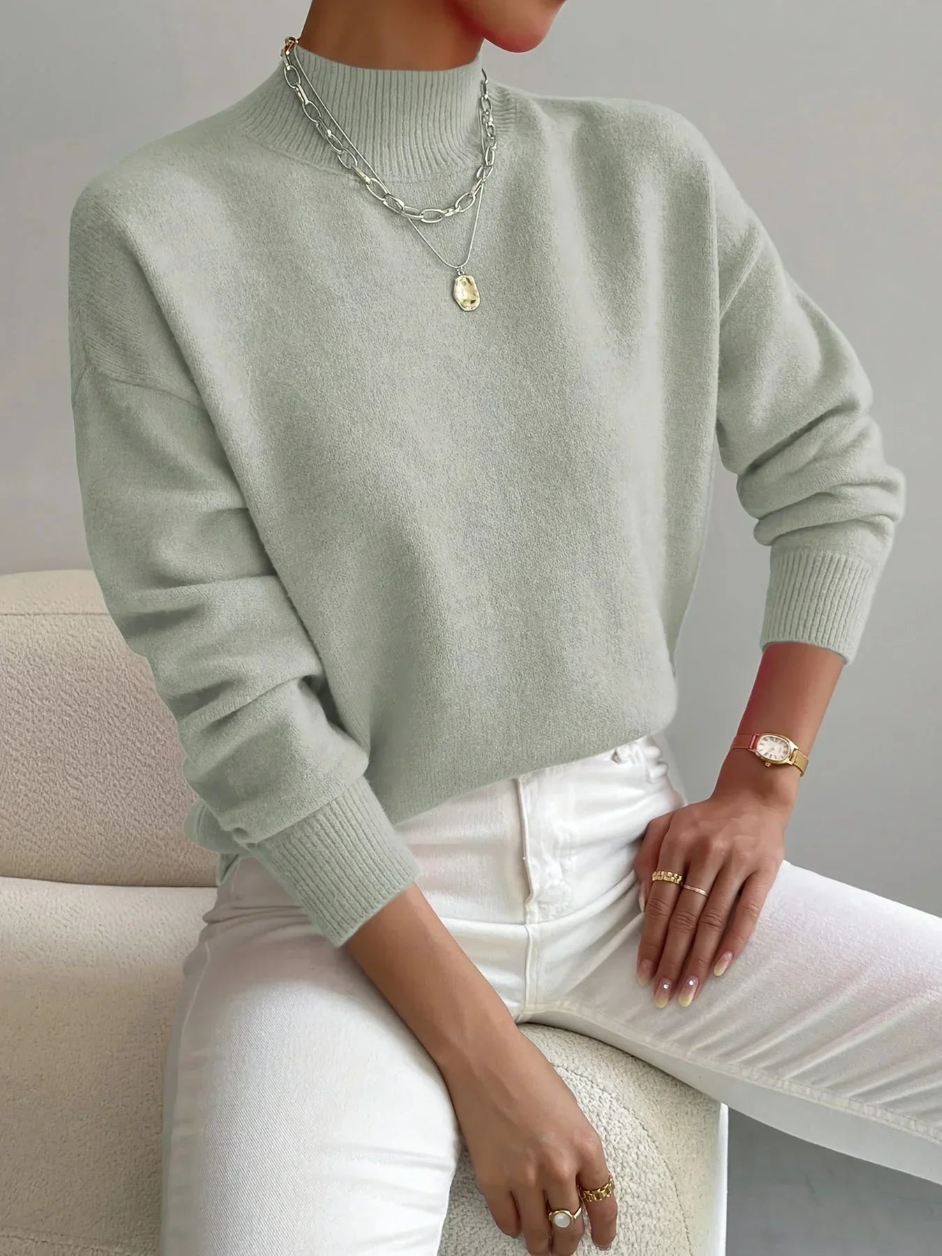 Pull féminin rose clair à col montant, en tissu extensible, avec manches longues pour un ajustement confortable.
