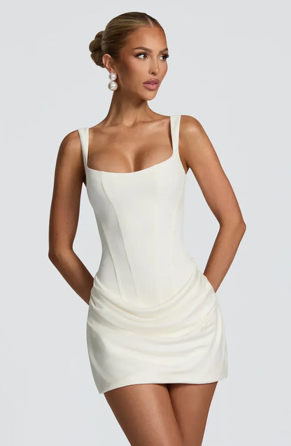 Robe courte femme drapée en blanc, avec corset ajusté et tissu léger pour une silhouette élégante et stylée.