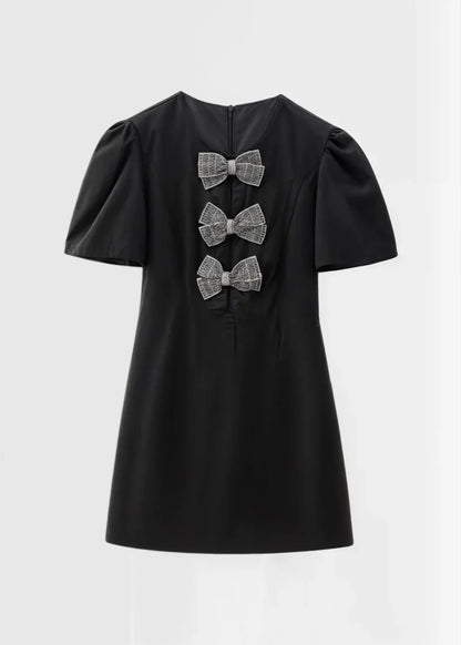Robe courte à pois avec nœuds, manches bouffantes en tissu léger, parfaite pour une soirée estivale.