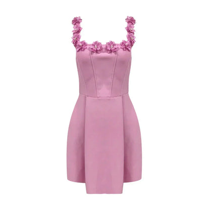 Robe courte rose sans manches avec encolure florale, en tissu léger, idéal pour les fêtes d'été. Détails floraux délicats.
