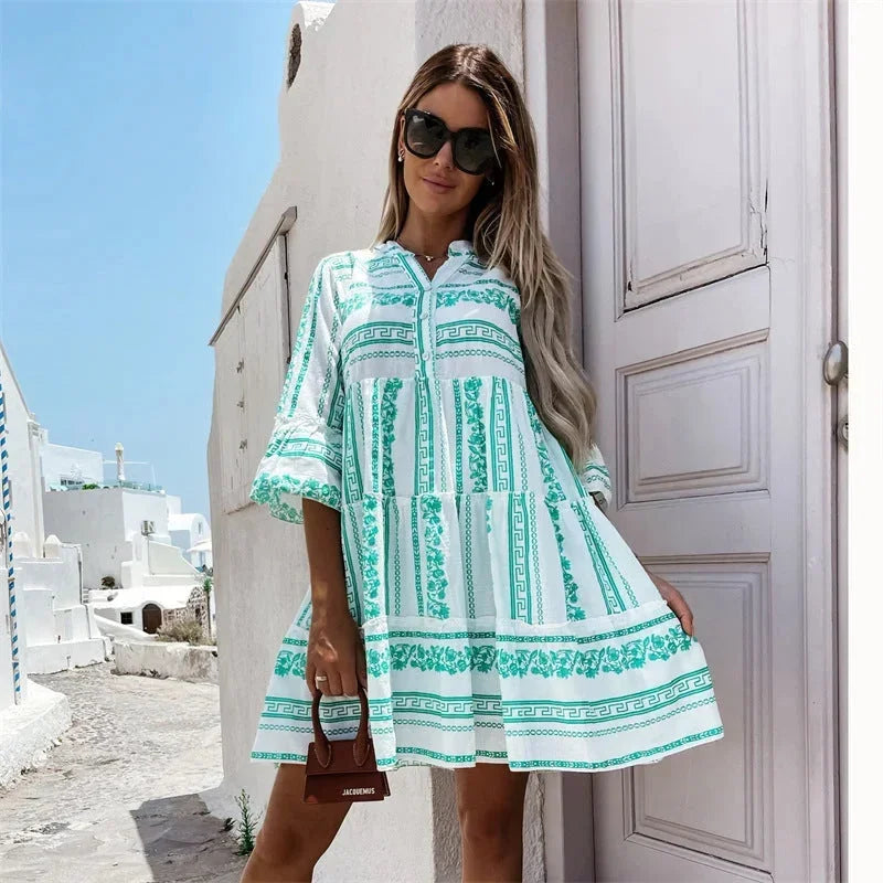 Robe courte évasée en coton léger, avec motifs estivaux, manches larges et col V, idéale pour les vacances balnéaires.