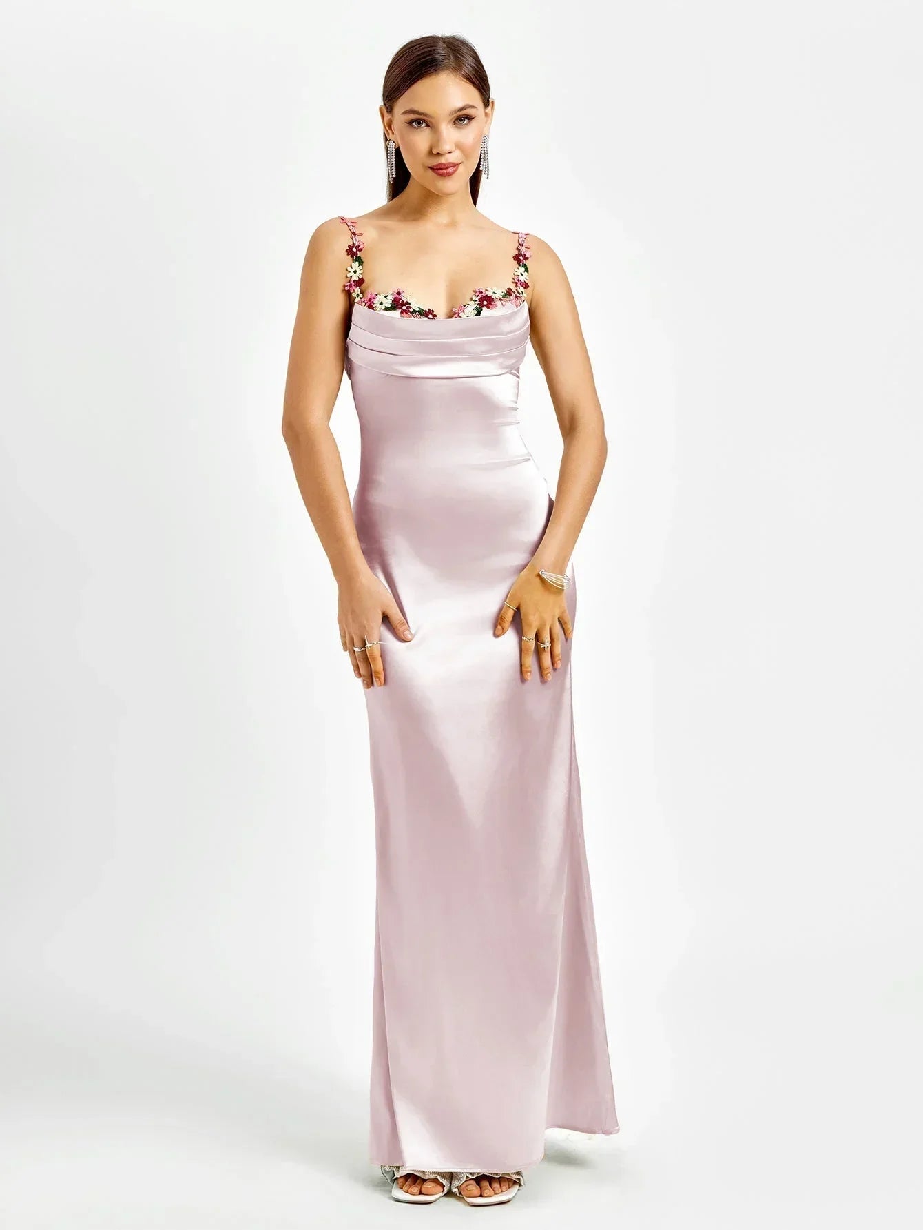 Robe longue ajustée sans manches en tissu léger avec ornements floraux délicats sur le bustier. Idéale pour les soirées.