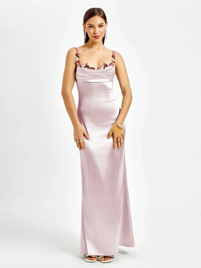 Robe longue ajustée sans manches en tissu léger avec ornements floraux délicats sur le bustier. Idéale pour les soirées.