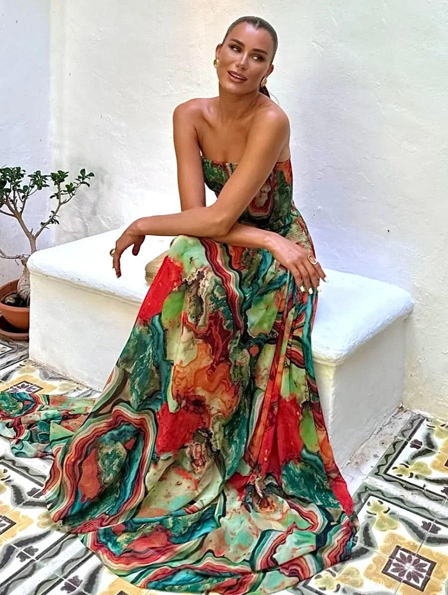Robe longue pour femme, avec buste dénudé, imprimé multicolore en tissu léger et fluide, idéale pour les occasions estivales.