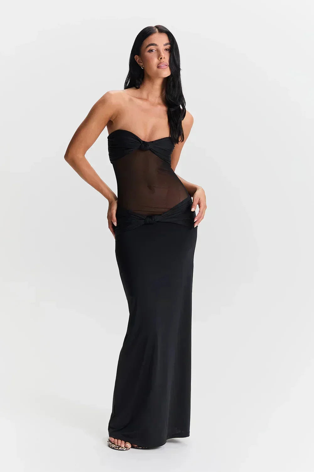 Robe longue noire à bustier, détail transparent au niveau du nœud, tissu fluide pour un look élégant.