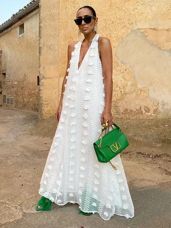 Robe longue blanche femme avec col halter et détails floraux légers, idéale pour des occasions estivales.