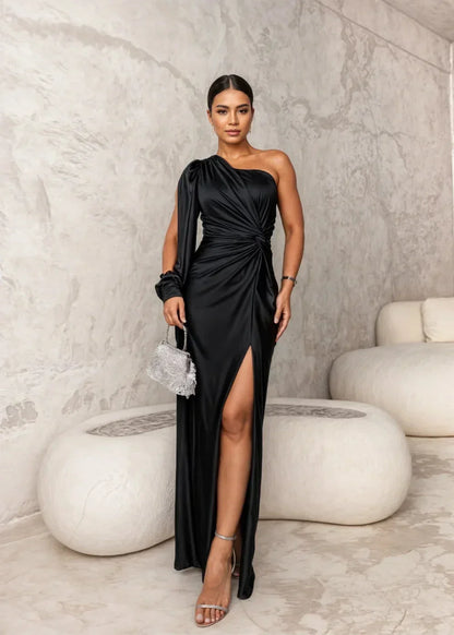 Robe longue noire à drapé sur une épaule, avec fente latérale, en tissu léger et fluide pour un style chic et raffiné.