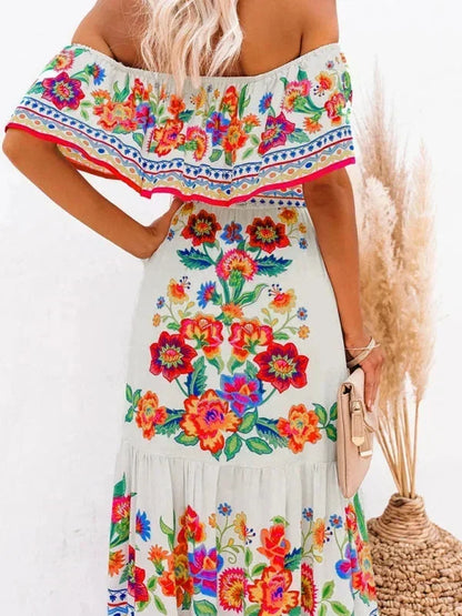 Robe longue femme en tissu léger à épaules dénudées, décorée de motifs floraux colorés sur un fond doux.