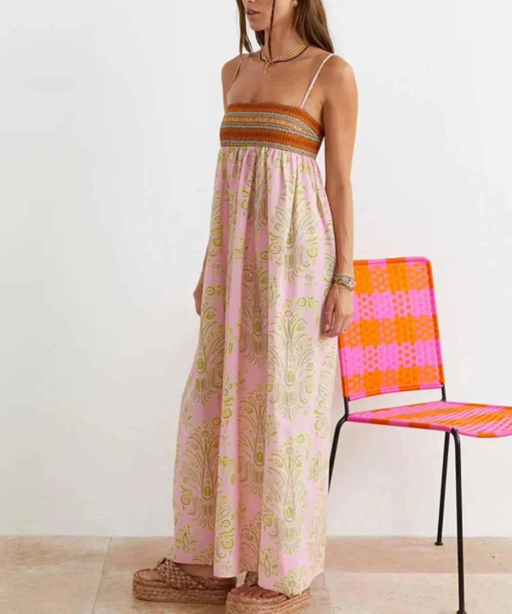 Robe longue rose boho à bretelles avec motifs estivaux, en tissu léger et fluide idéal pour les journées ensoleillées.
