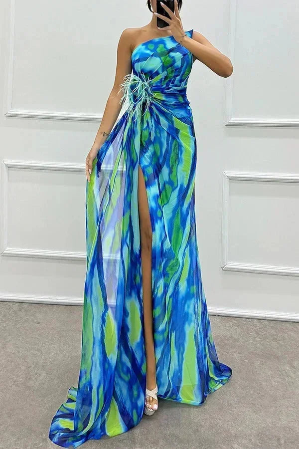 Robe longue bleue à motifs, avec fente élégante et bretelle, en tissu léger et fluide, idéale pour une soirée.