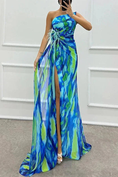 Robe longue bleue à motifs, avec fente élégante et bretelle, en tissu léger et fluide, idéale pour une soirée.