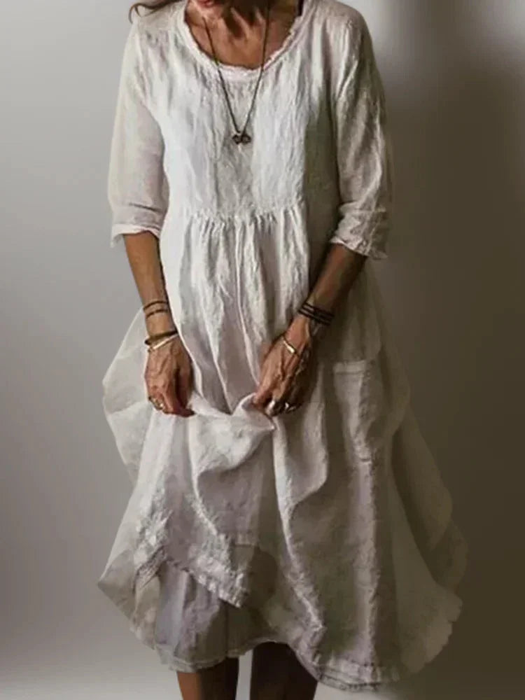Robe longue blanche à volants, col en V, manches 3/4, en tissu léger et fluide, parfaite pour les occasions estivales.