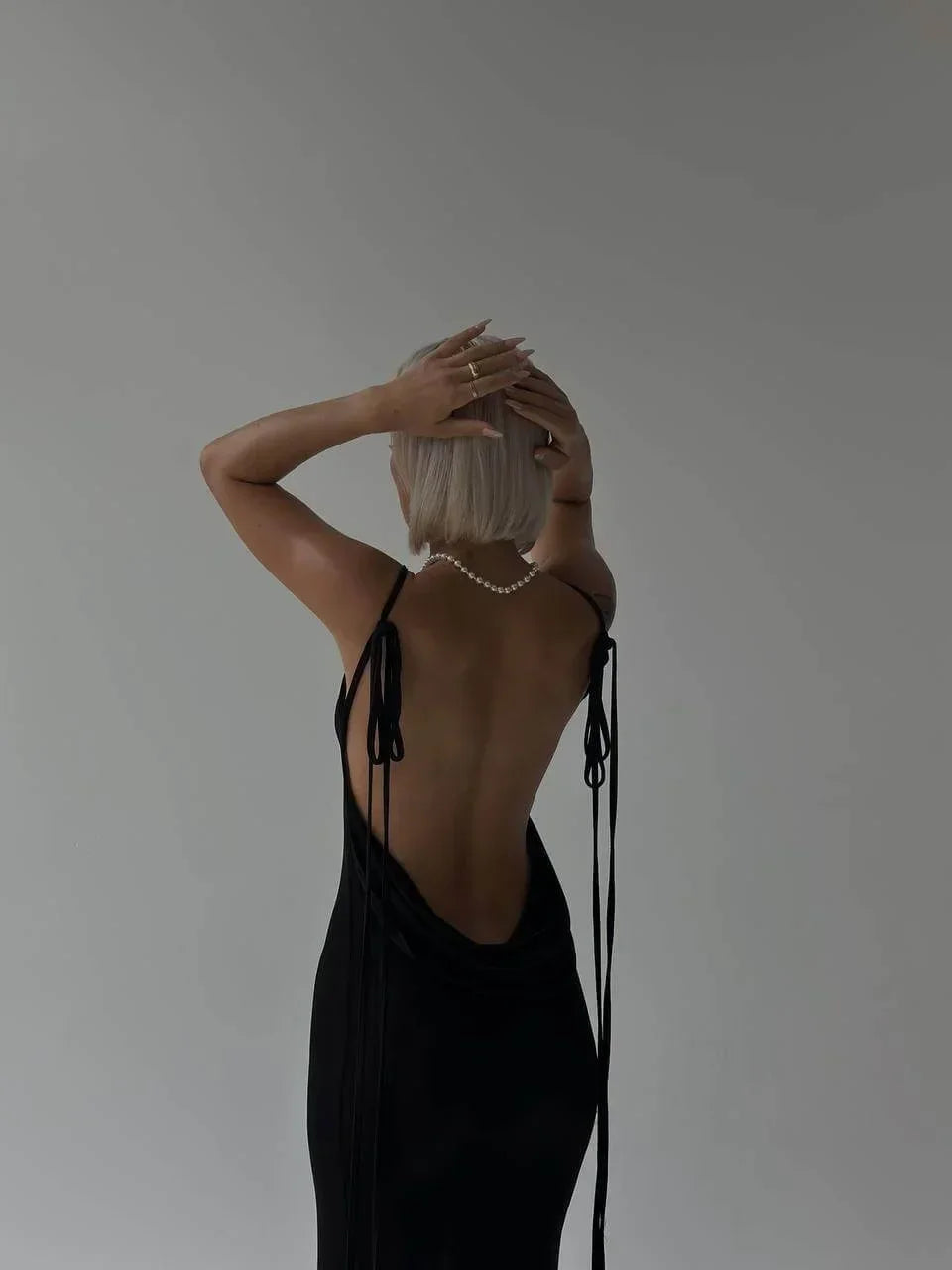 Robe longue élégante en tissu léger, dos nu avec liens ajustables pour un ajustement personnalisé et un style raffiné.
