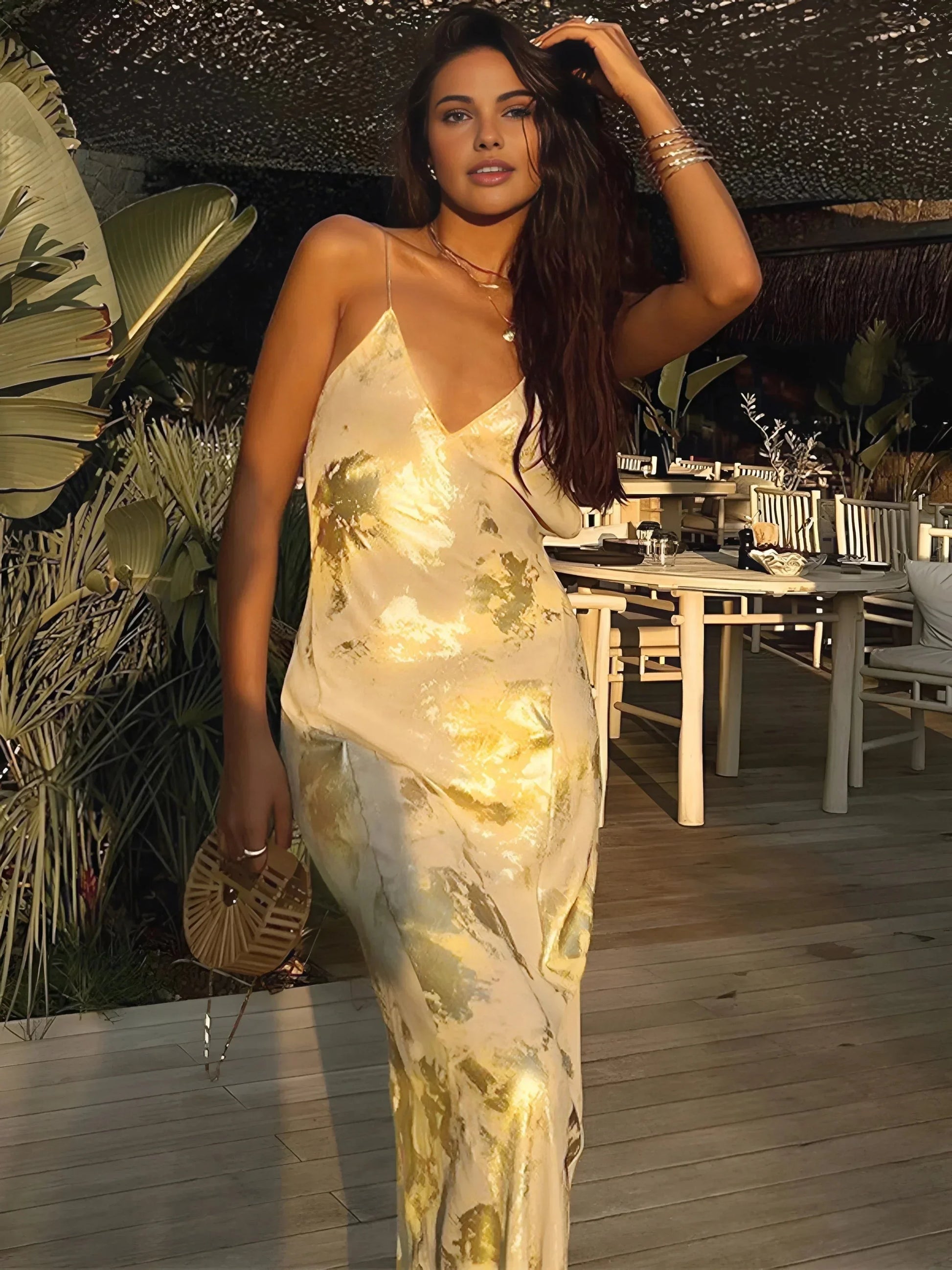 Robe longue satinée dorée avec bretelles, silhouette fluide et tissu léger pour une soirée élégante.