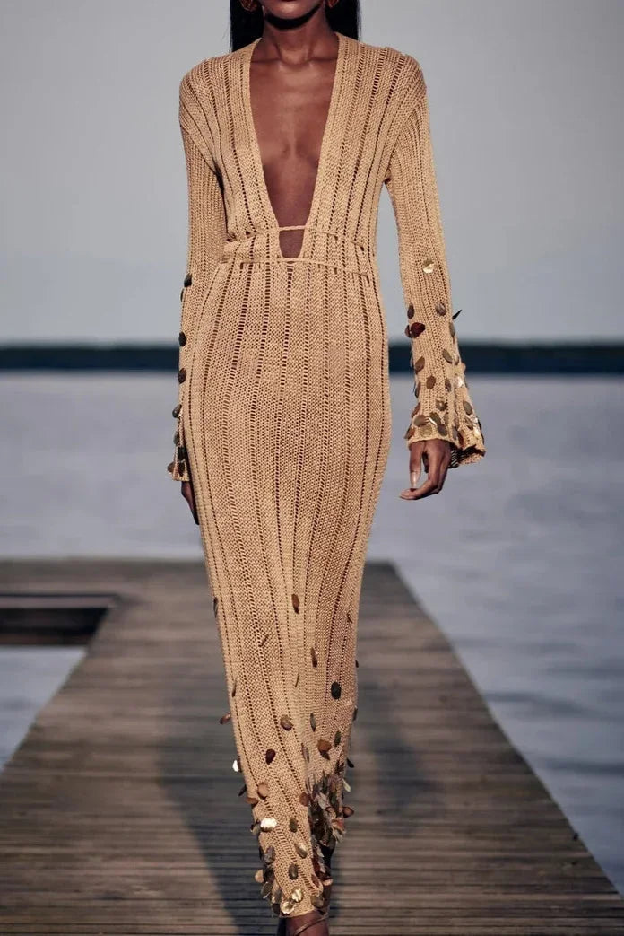 Robe longue dorée à sequins, manches longues et décolleté plongeant, en tissu transparent pour un look élégant en soirée.